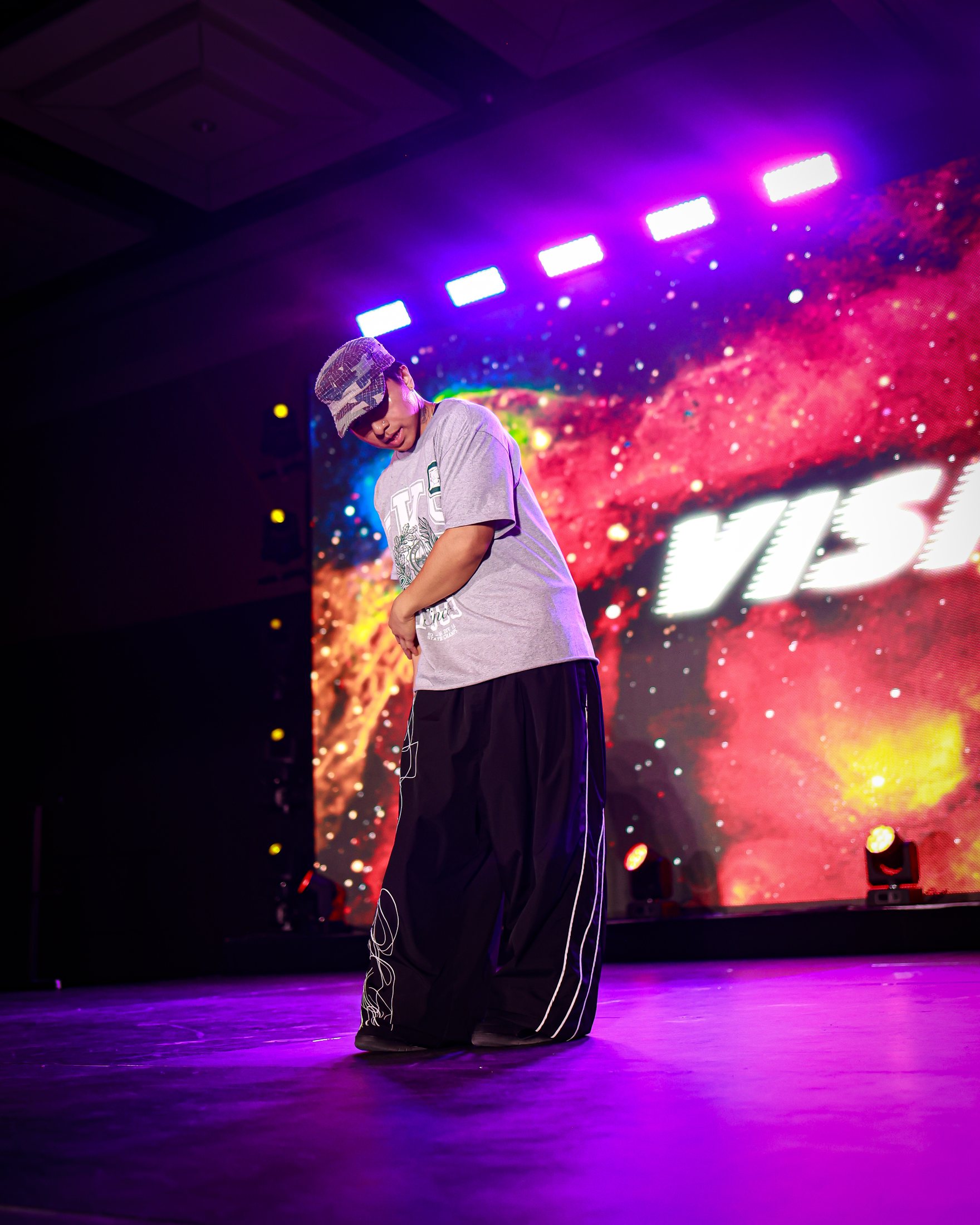Solo performer mid-move on stage under LED lighting during a VISION battle segment.